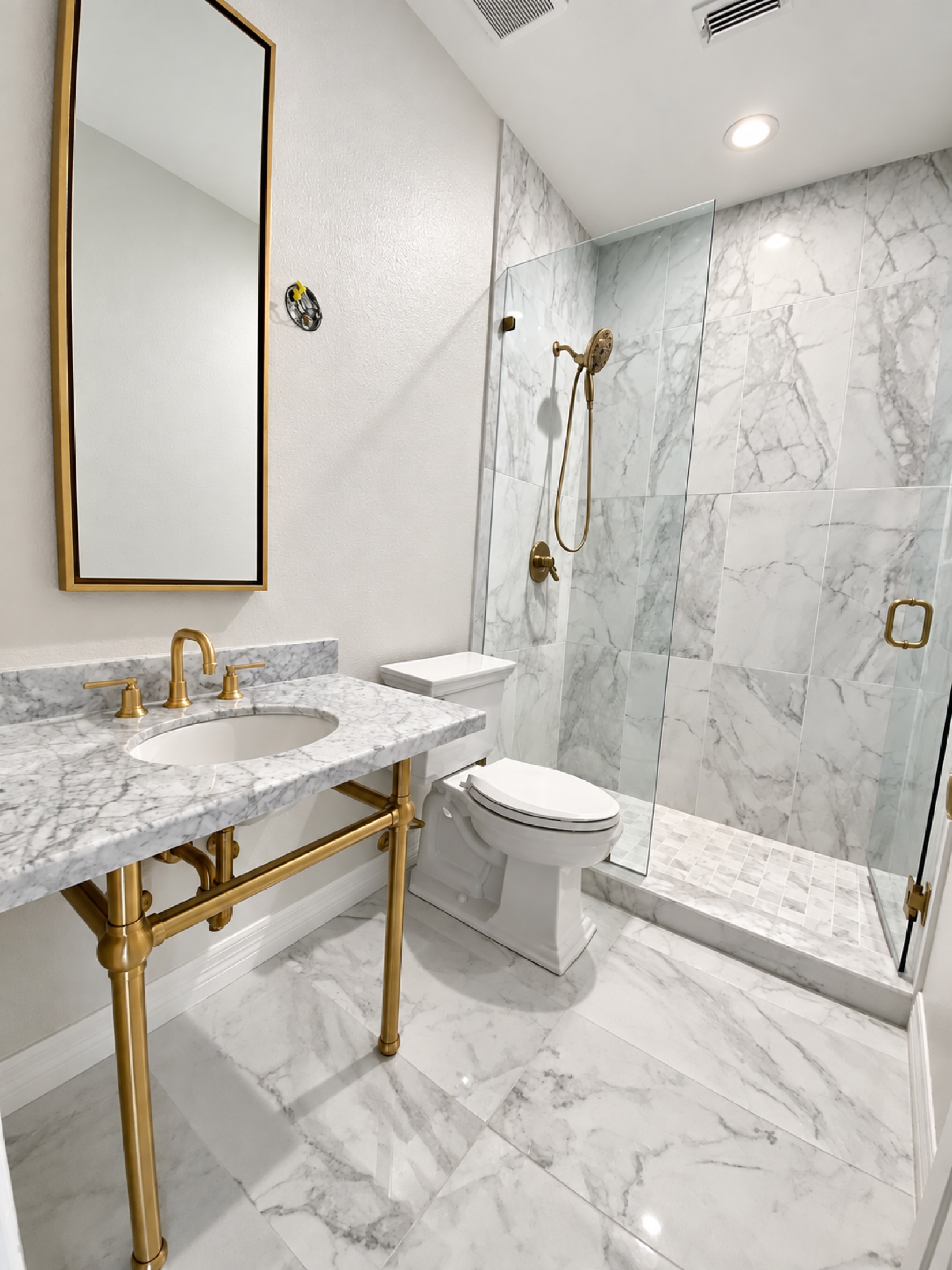 White marble bathroom with brass fixtures and a glass-enclosed shower