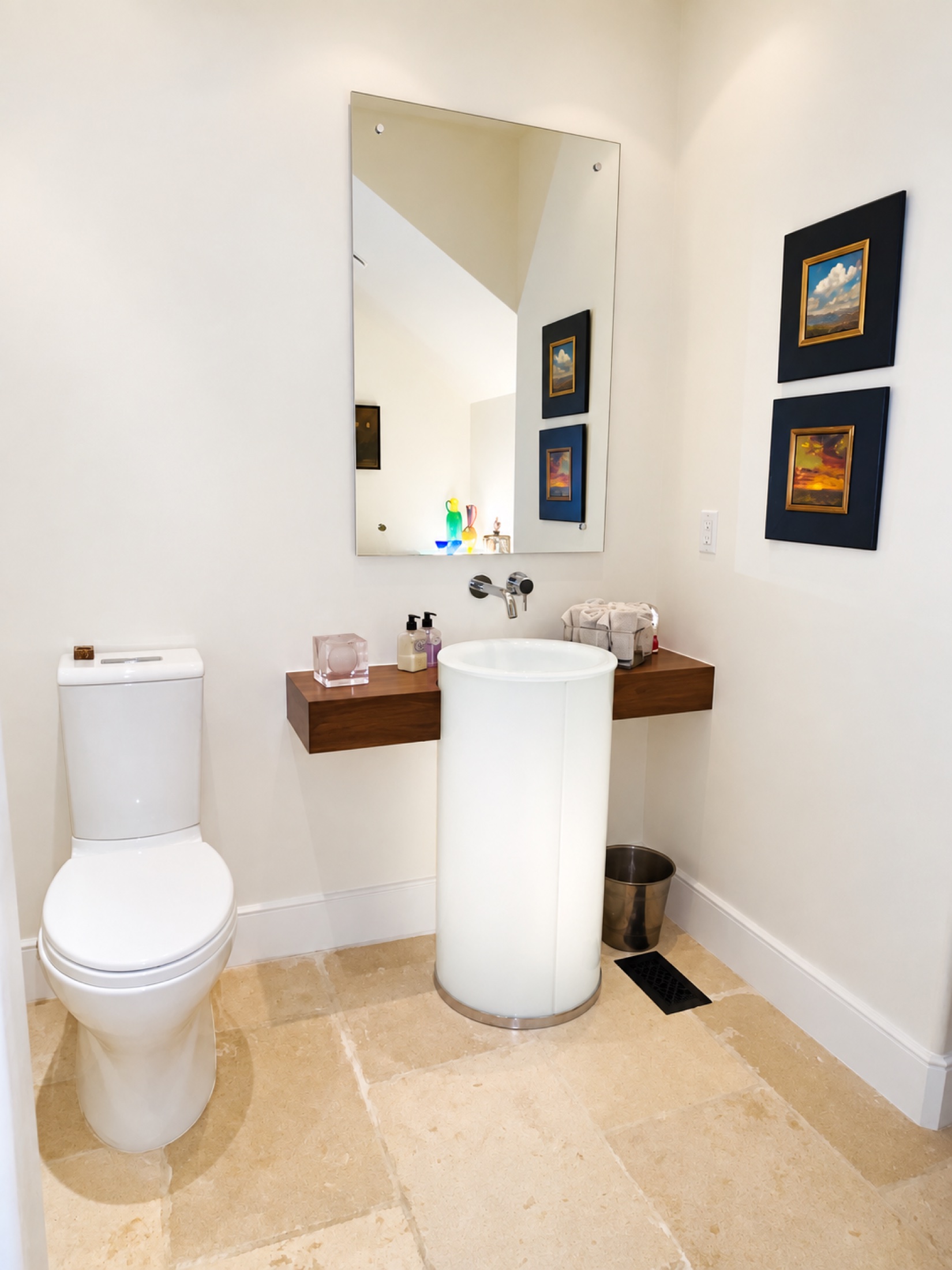 Powder room with a white pedestal sink, floating wood shelf and framed art