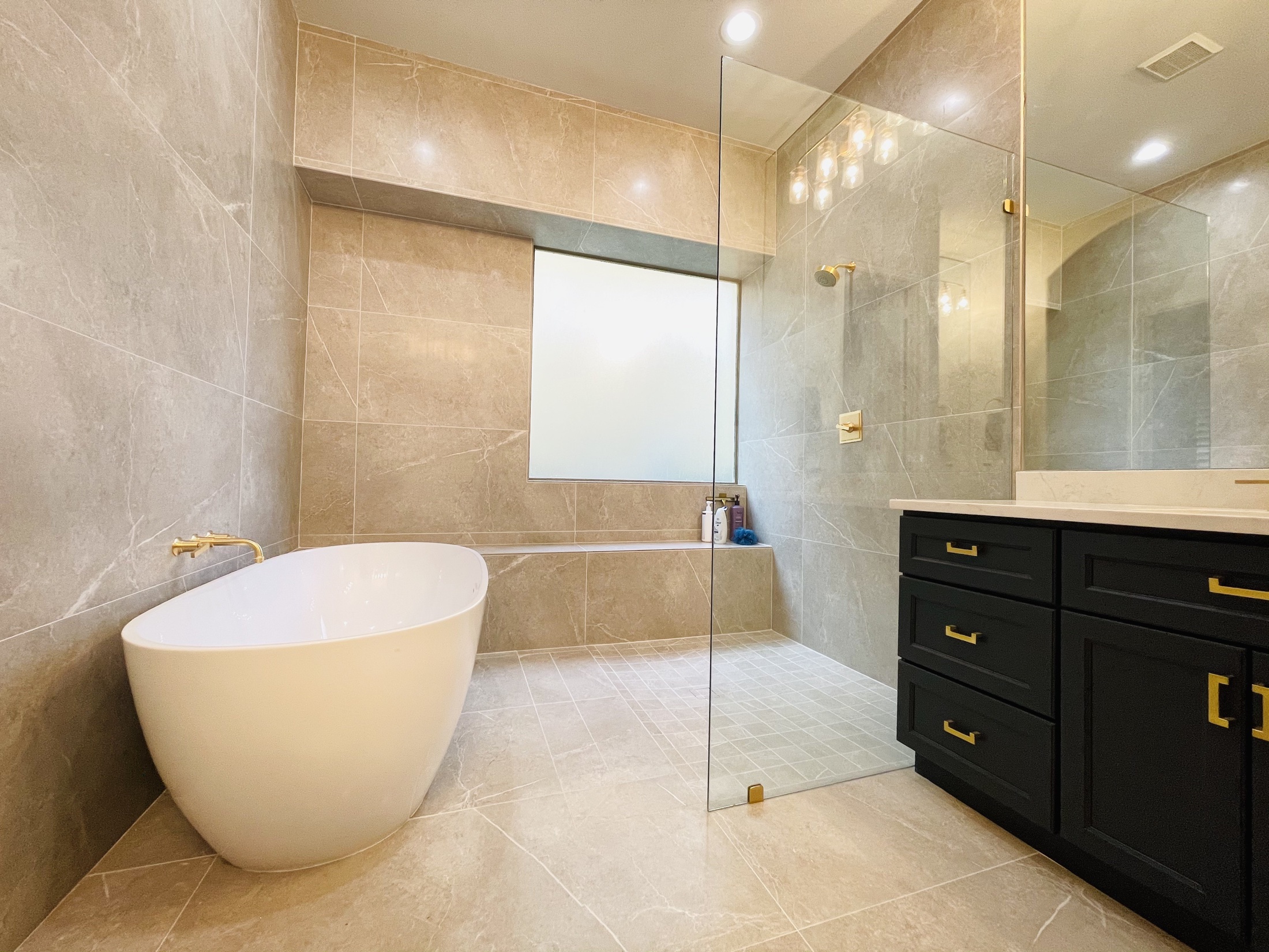 Neutral bathroom with a freestanding tub, glass shower and dark vanity