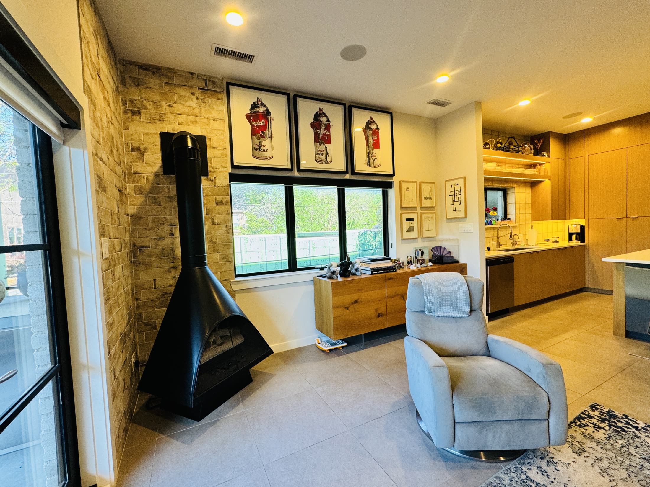 Interior with a sculptural black fireplace, stone wall and warm wood cabinetry