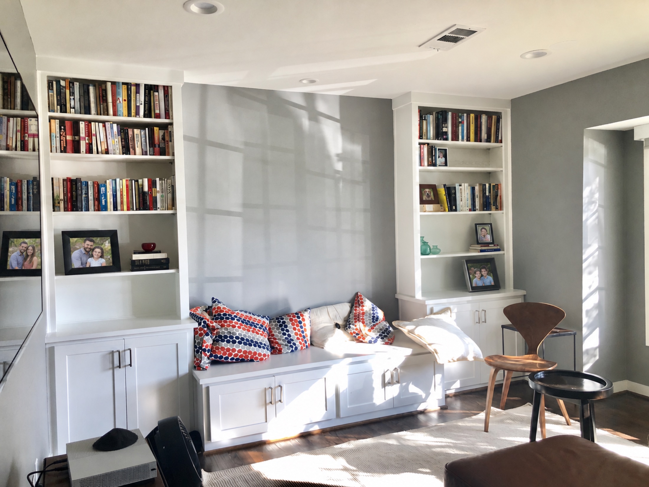 White built-in bookcases framing a window-seat bench with patterned cushions