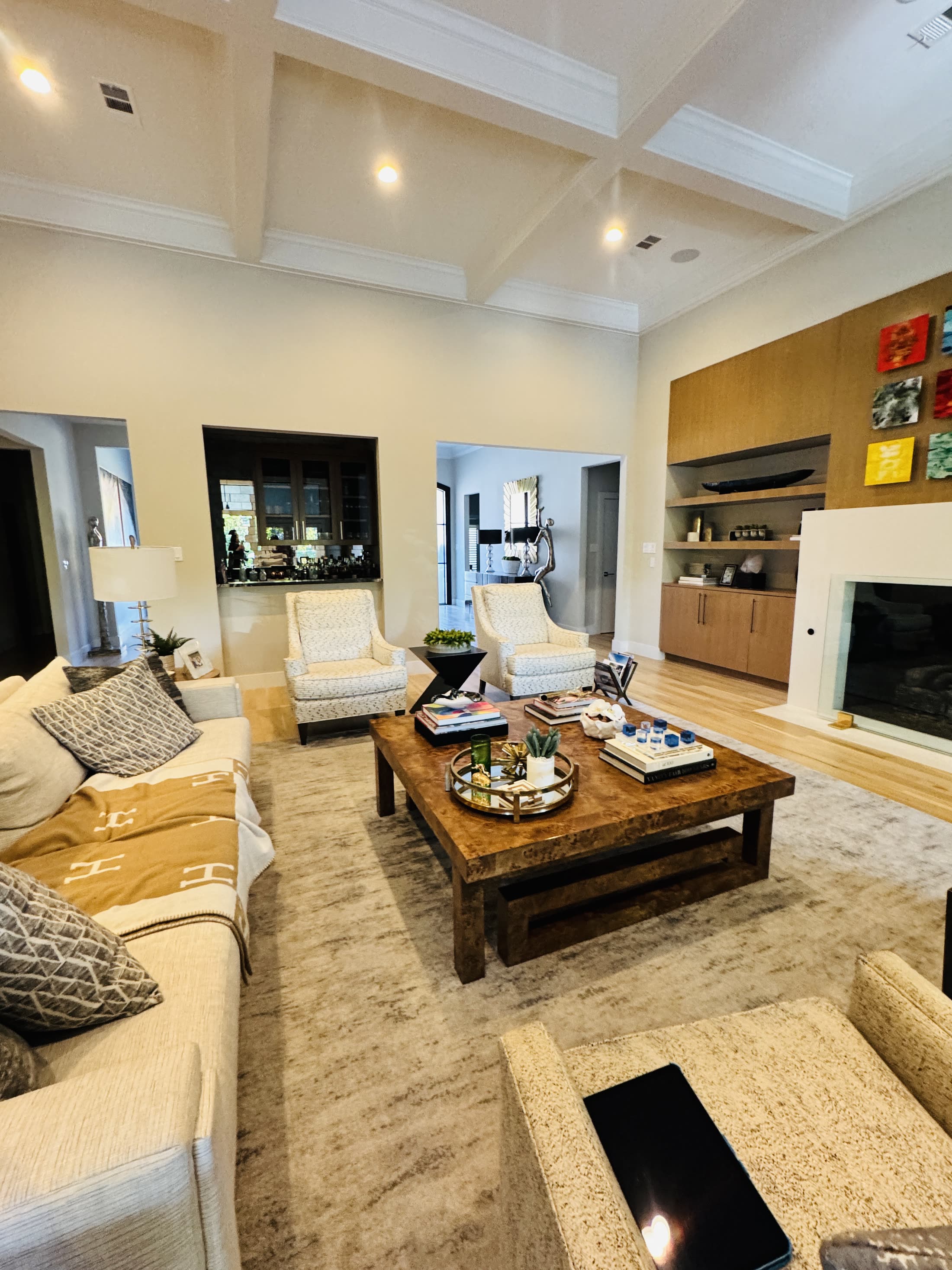 Furnished living room with a tall coffered ceiling, fireplace and built-in cabinetry