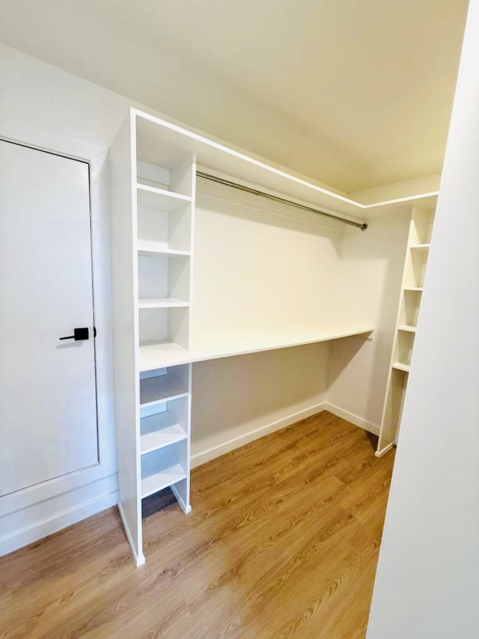 Finished white walk-in closet with built-in shelves and hanging space