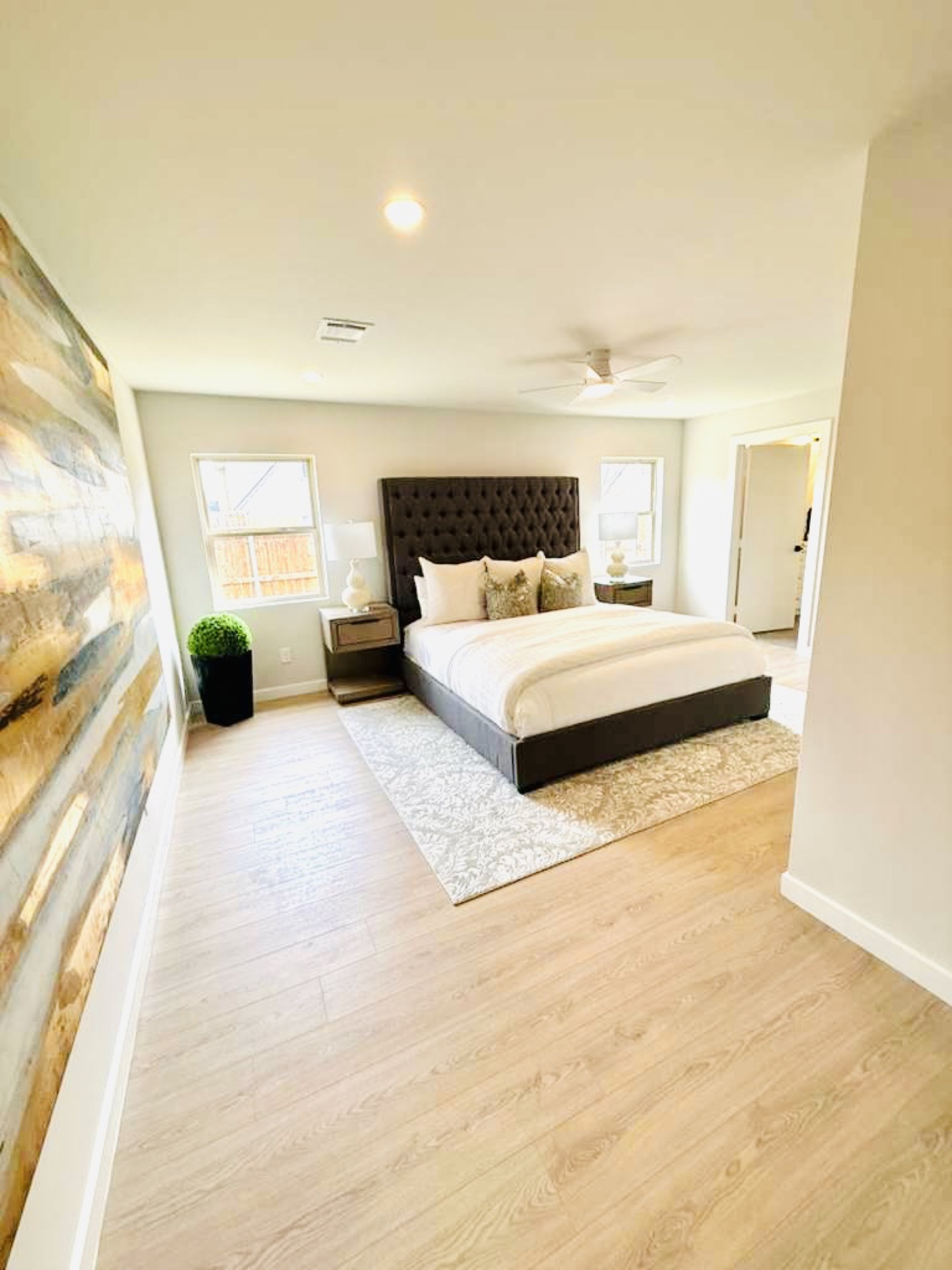 Neutral bedroom with a dark upholstered bed and pale wood floors