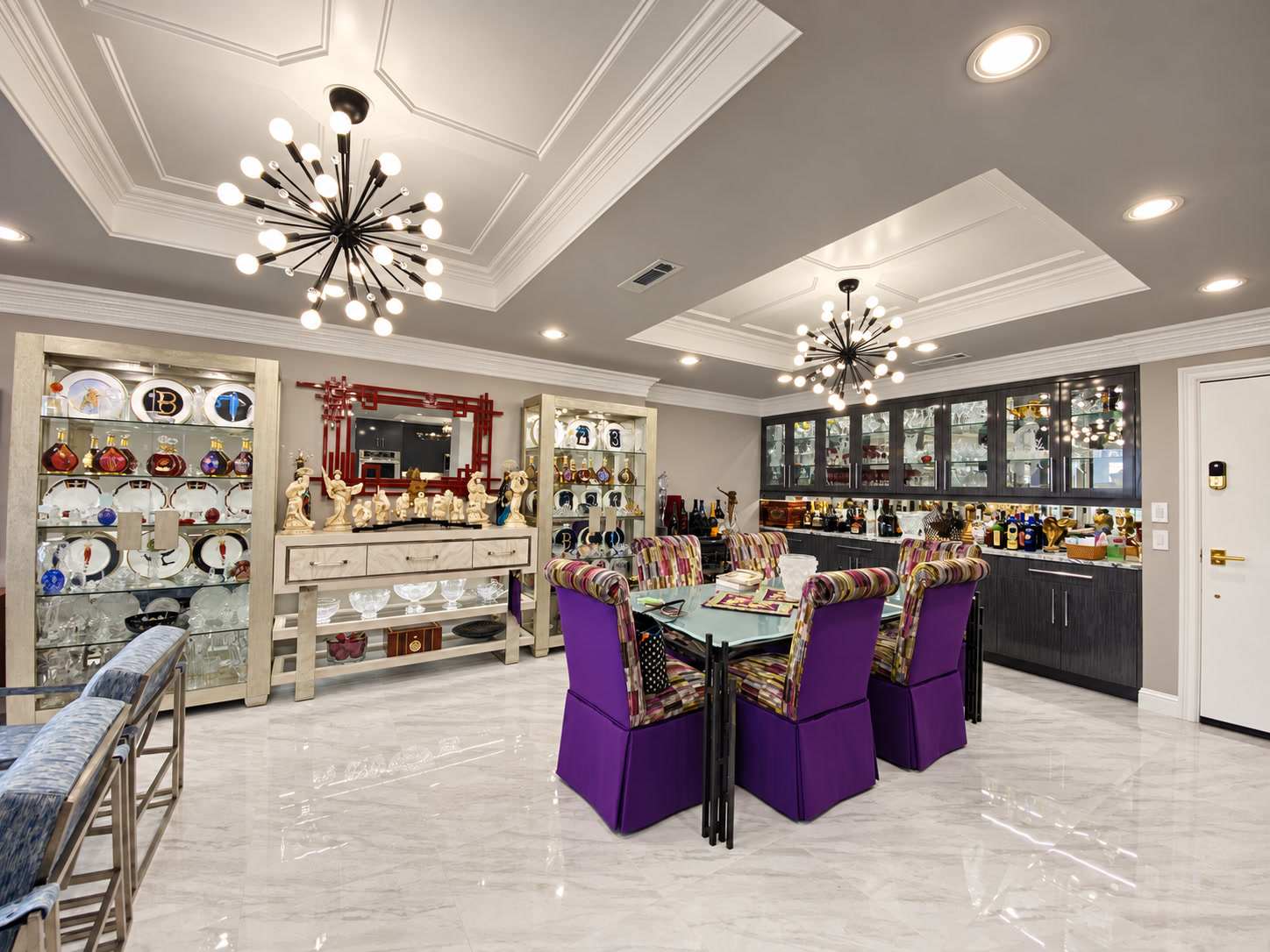 Ornate dining and entertaining room with purple chairs, display cabinets and statement chandeliers
