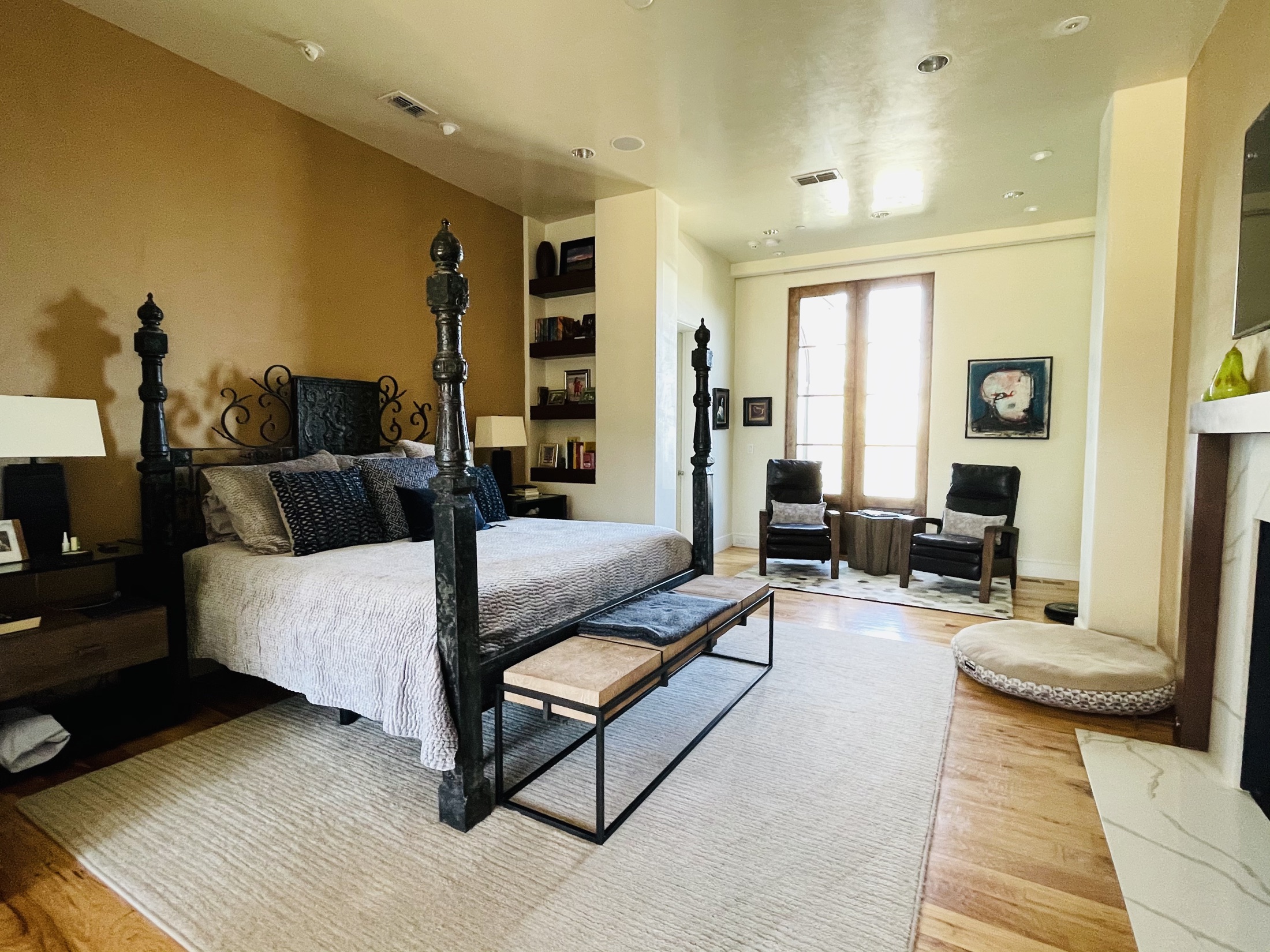 Furnished primary bedroom with dark four-poster bed and a seating area
