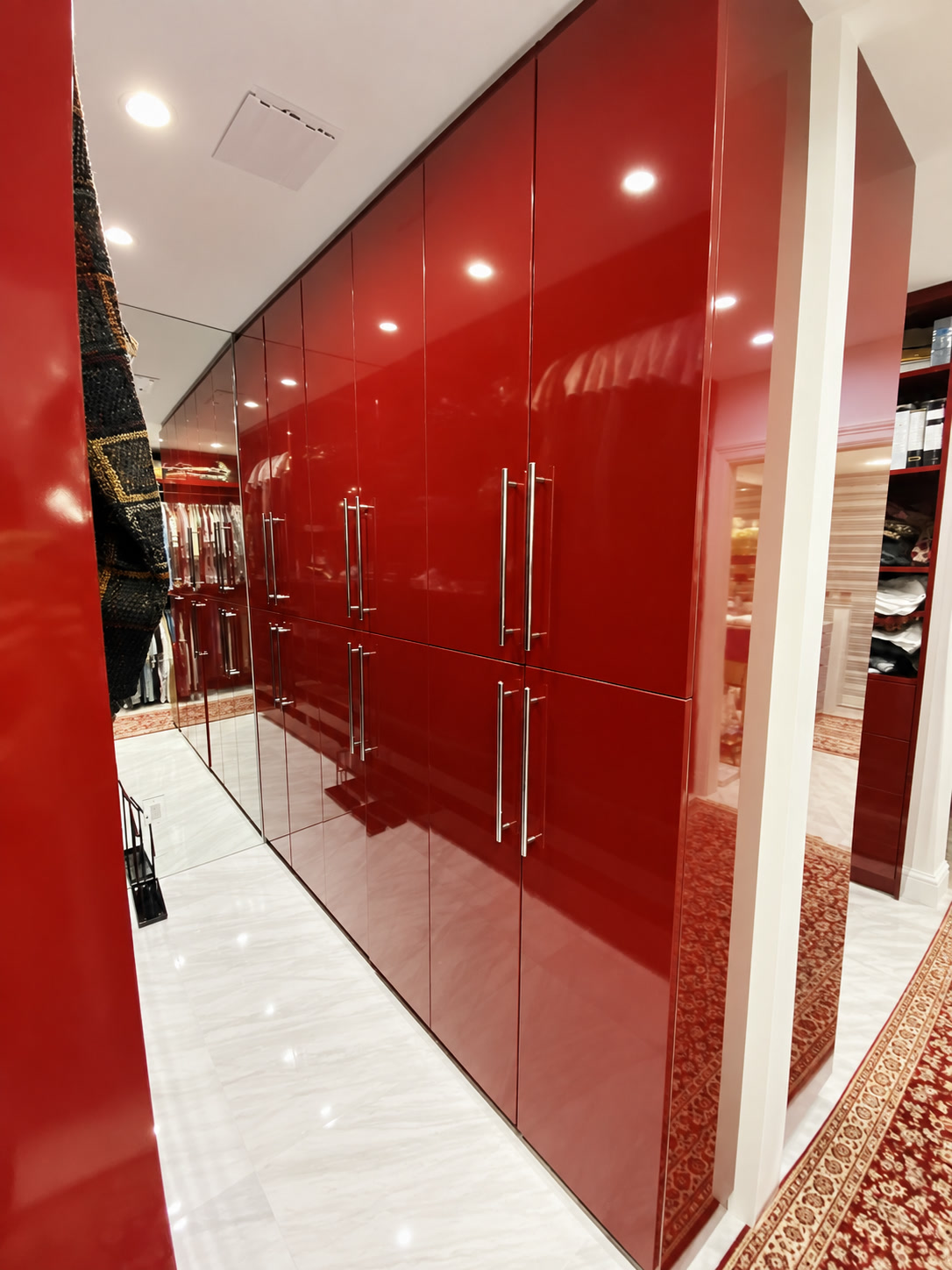 Glossy red built-in closet cabinetry with pale tile flooring