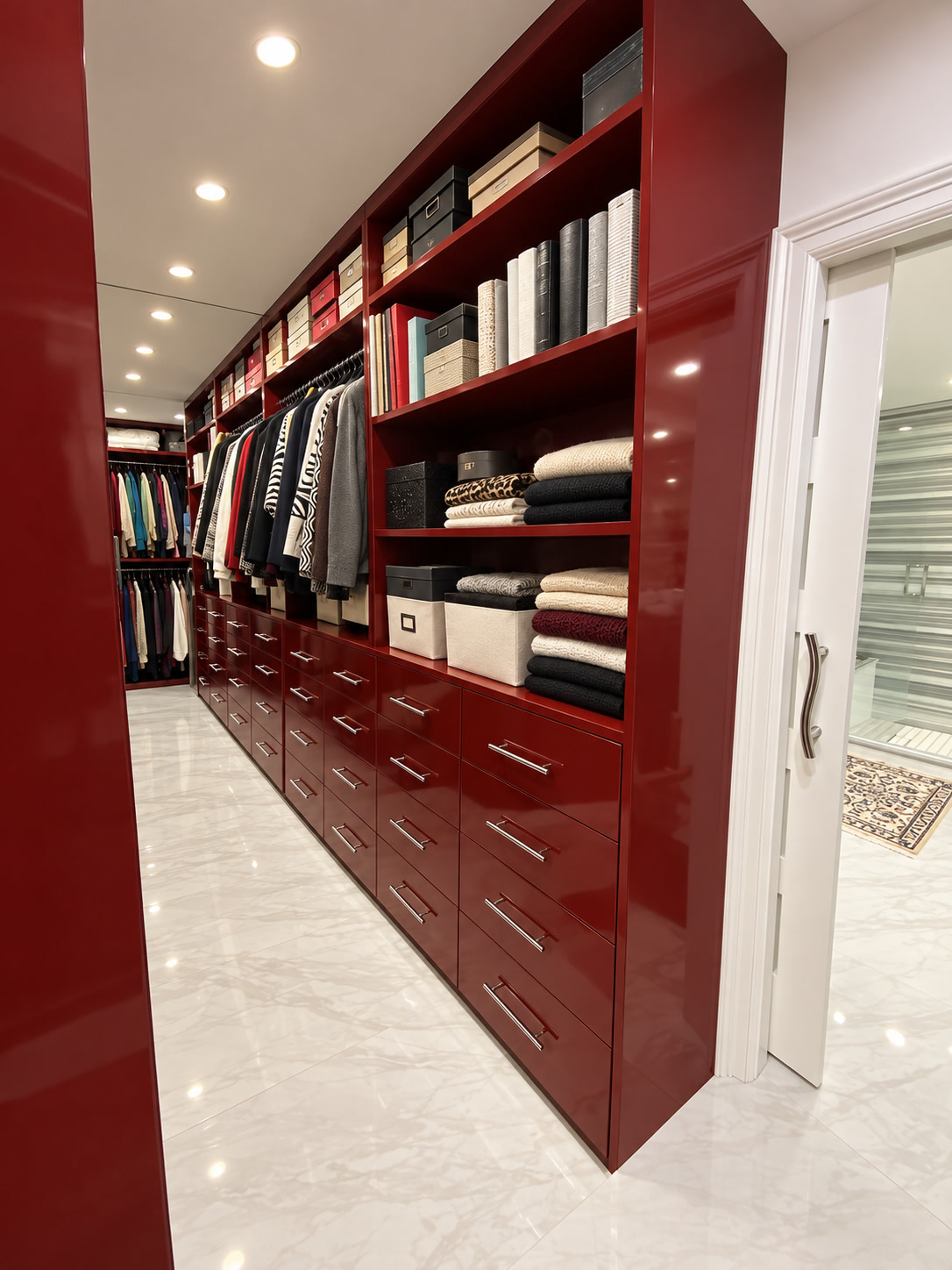 Walk-in closet with glossy red built-in drawers, open shelves and neatly arranged clothing