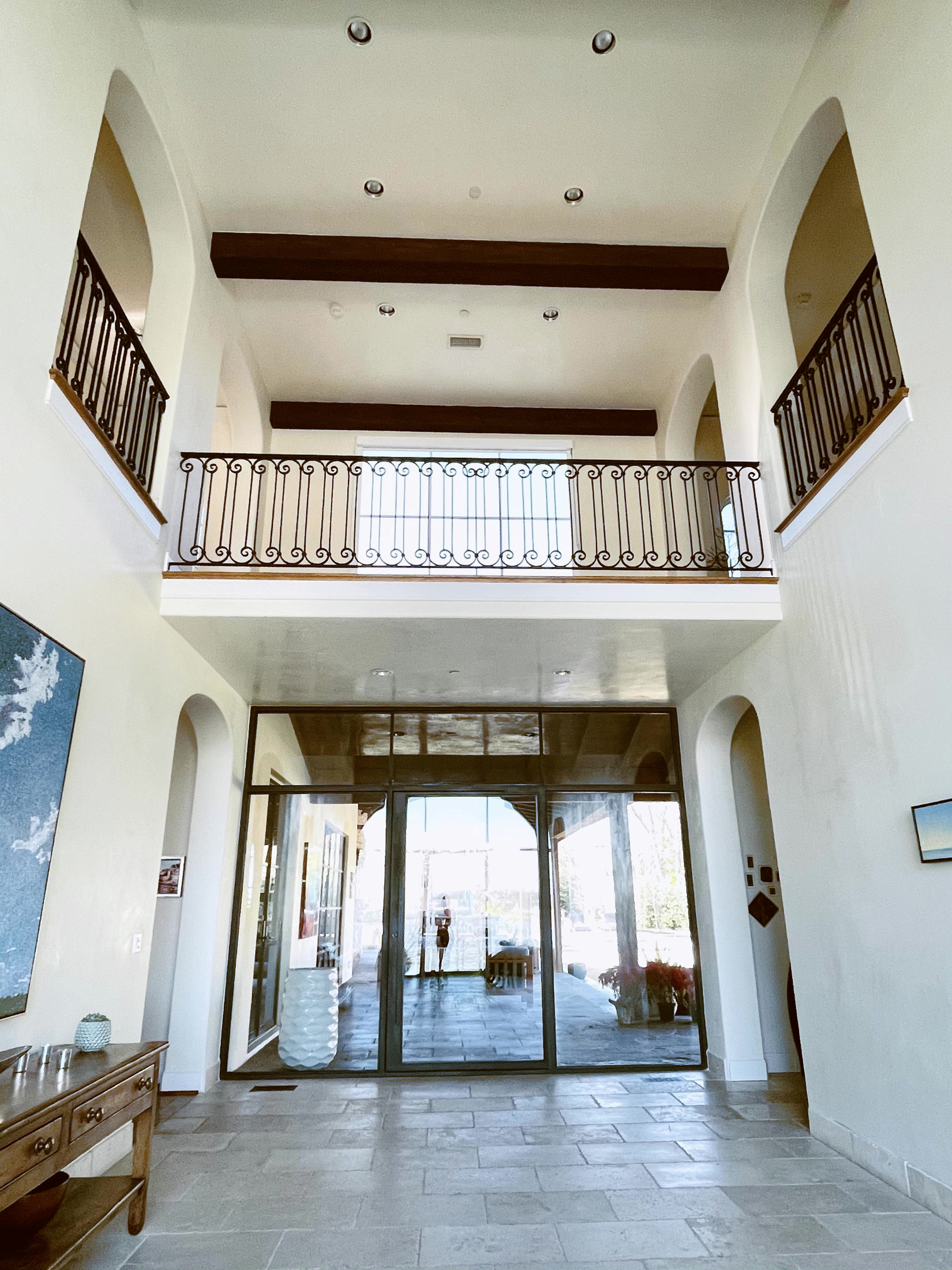 Two-story entry with black iron balcony railing and large glass doors