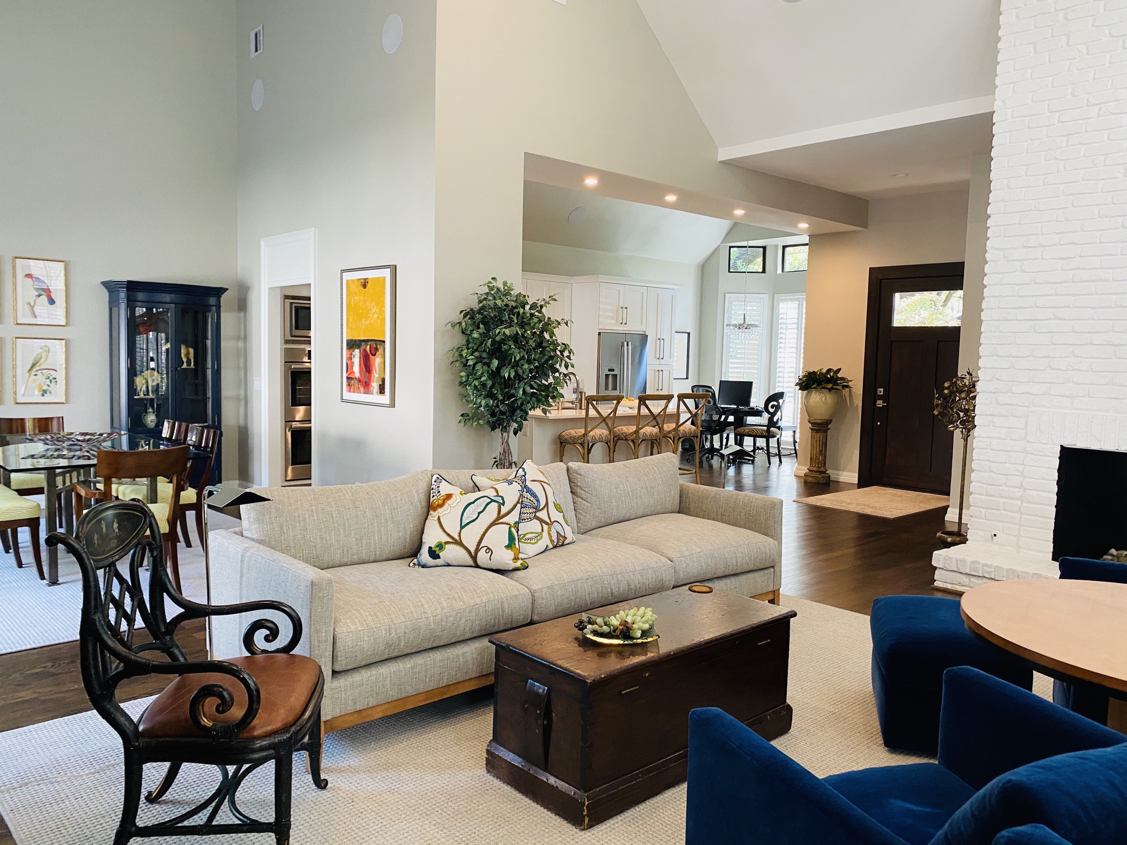 Open living and dining room beside a white brick fireplace and kitchen