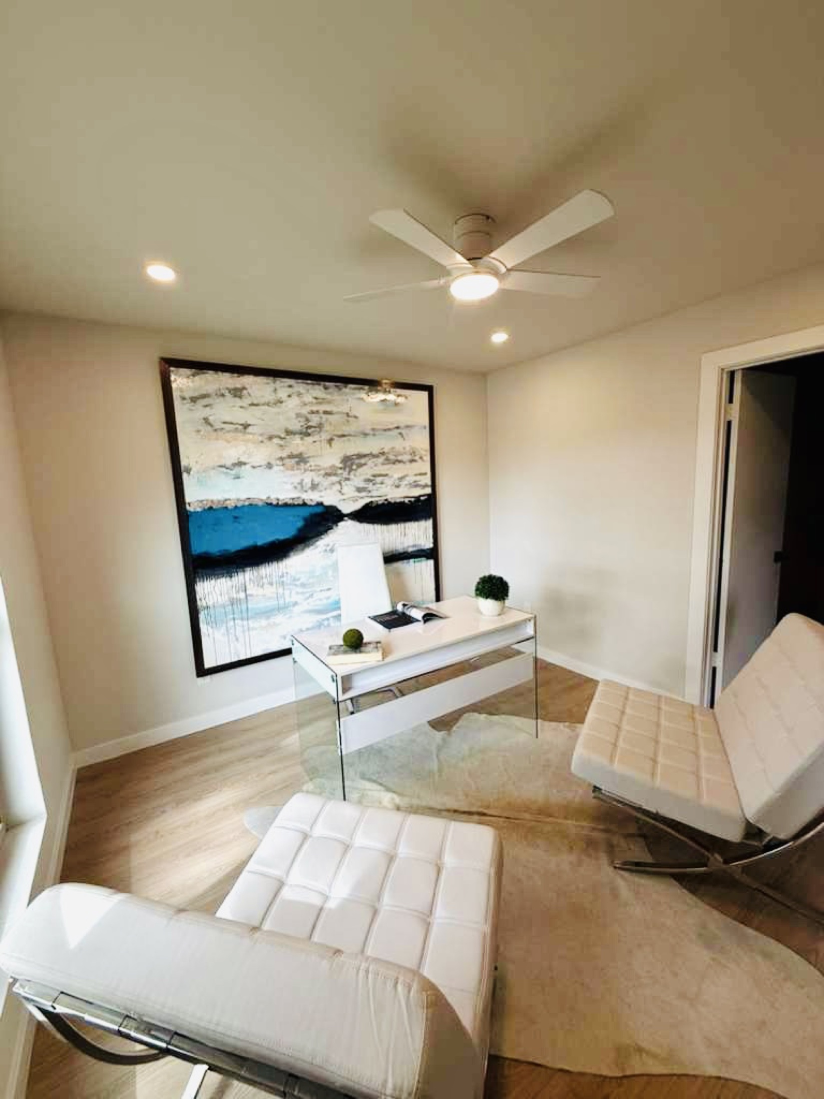 Bright home office with white seating and a large abstract painting