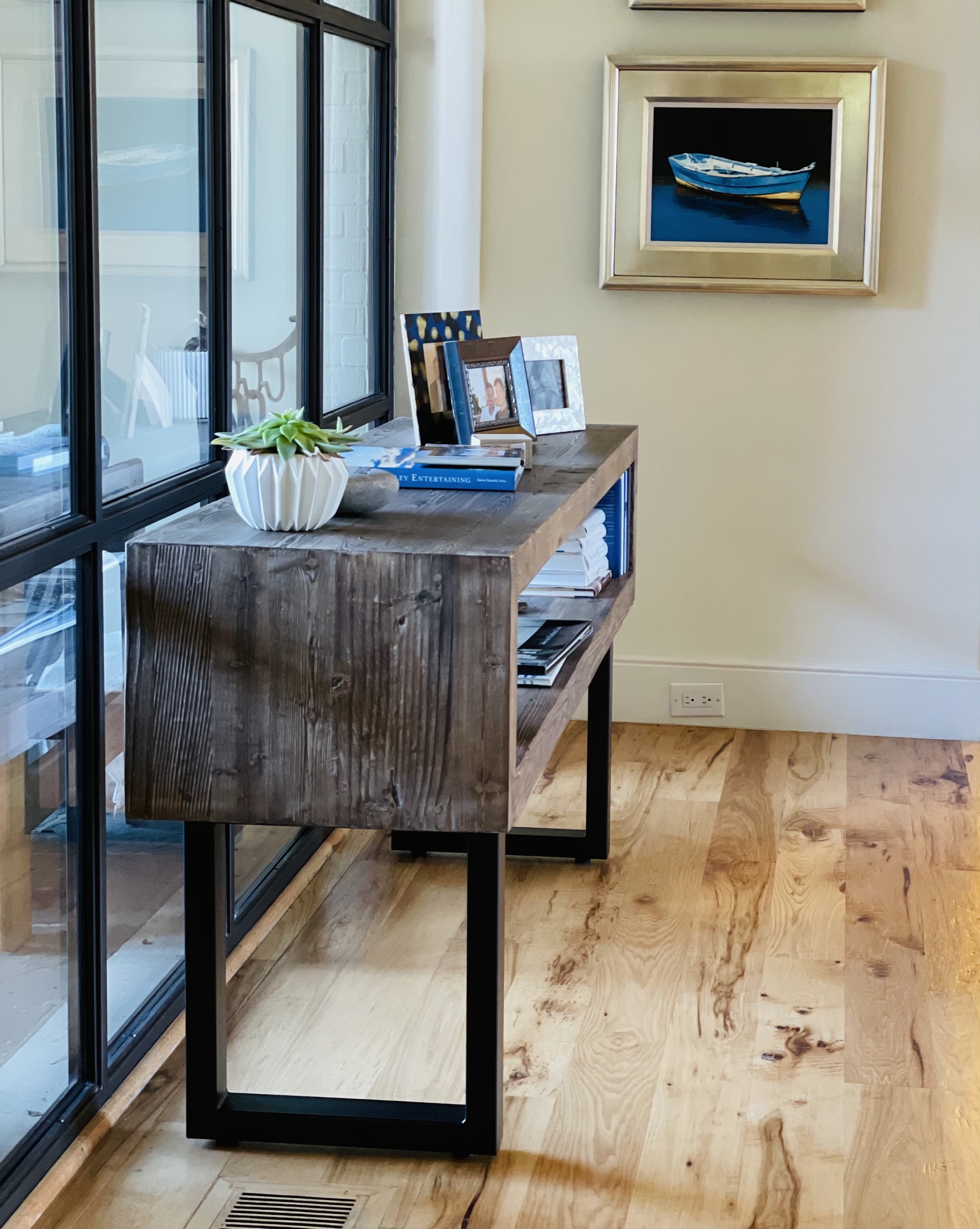 Wood console table beside black-framed floor-to-ceiling windows