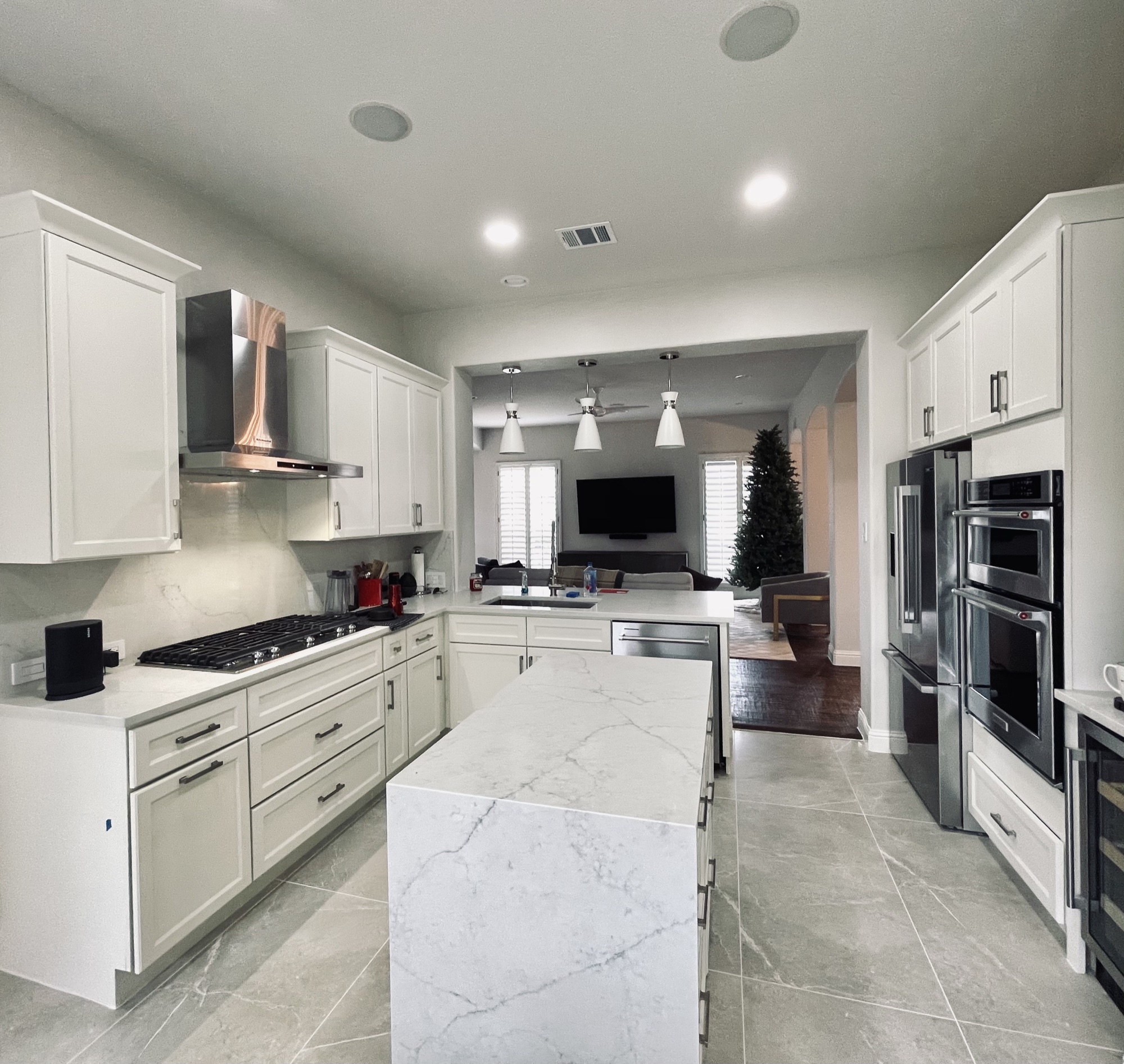 White kitchen with copper range hood and marble waterfall island