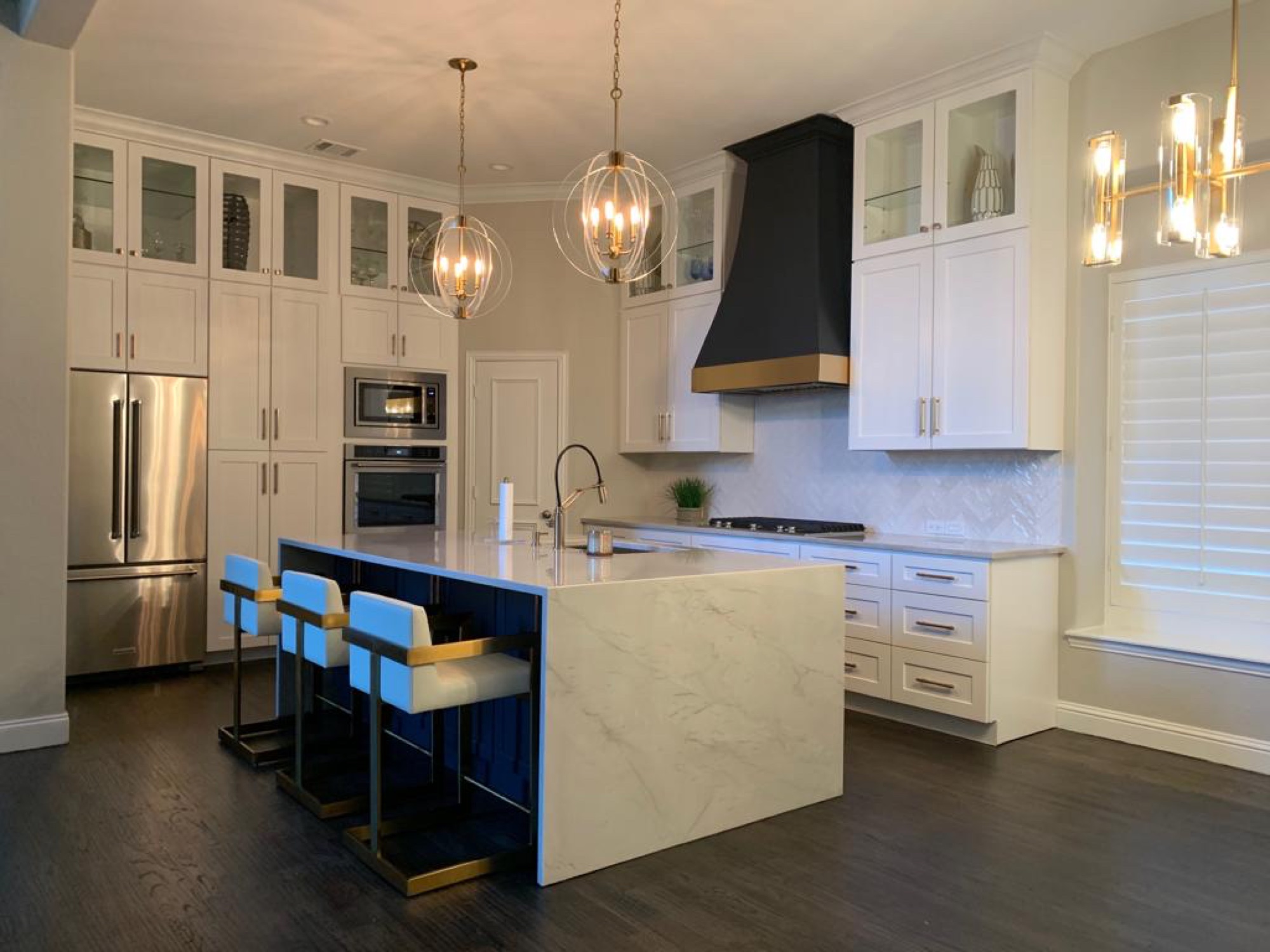 White kitchen with black range hood, gold trim and blue island