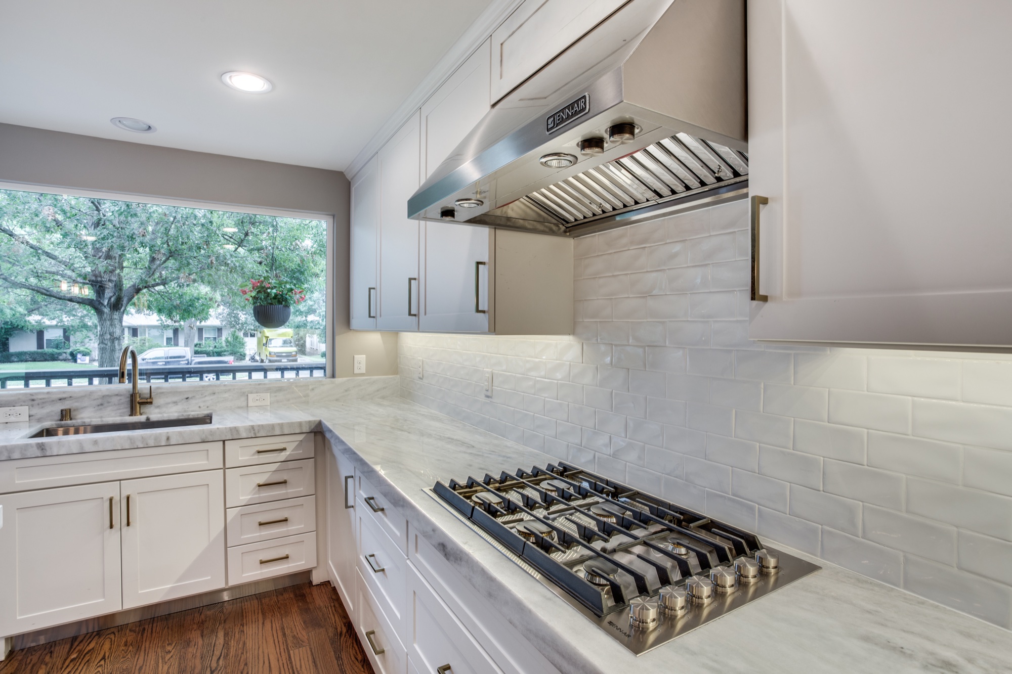 Close view of stainless range hood and cooktop in a white kitchen