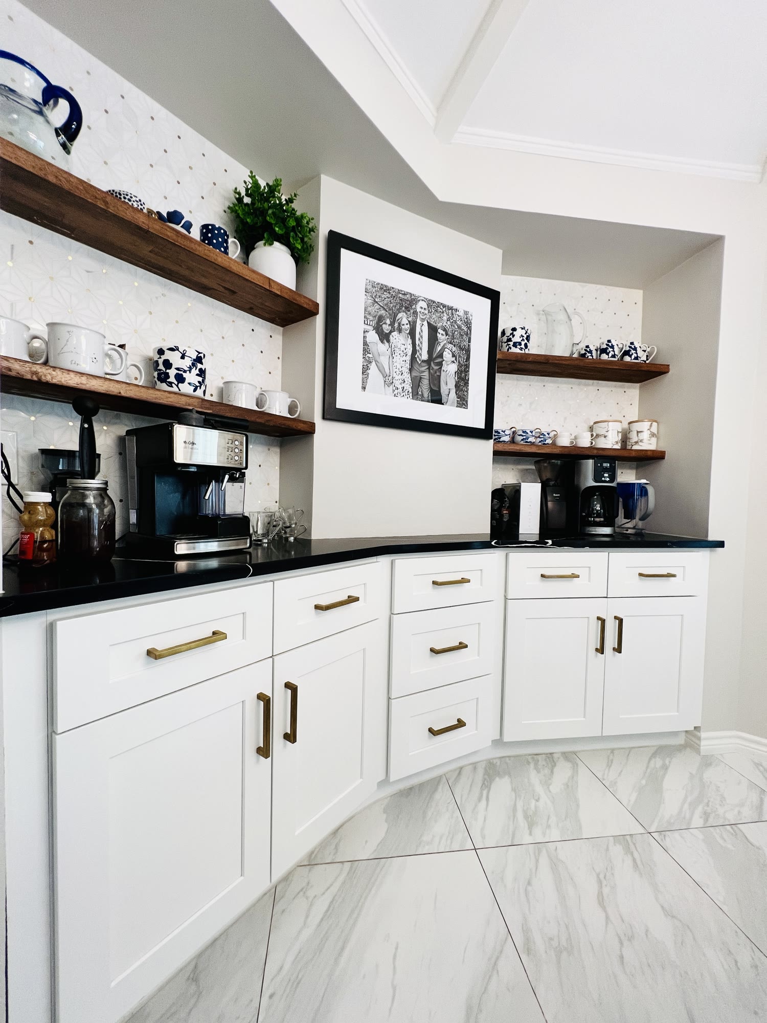 Built-in coffee station with white cabinets, wood shelves and black countertop