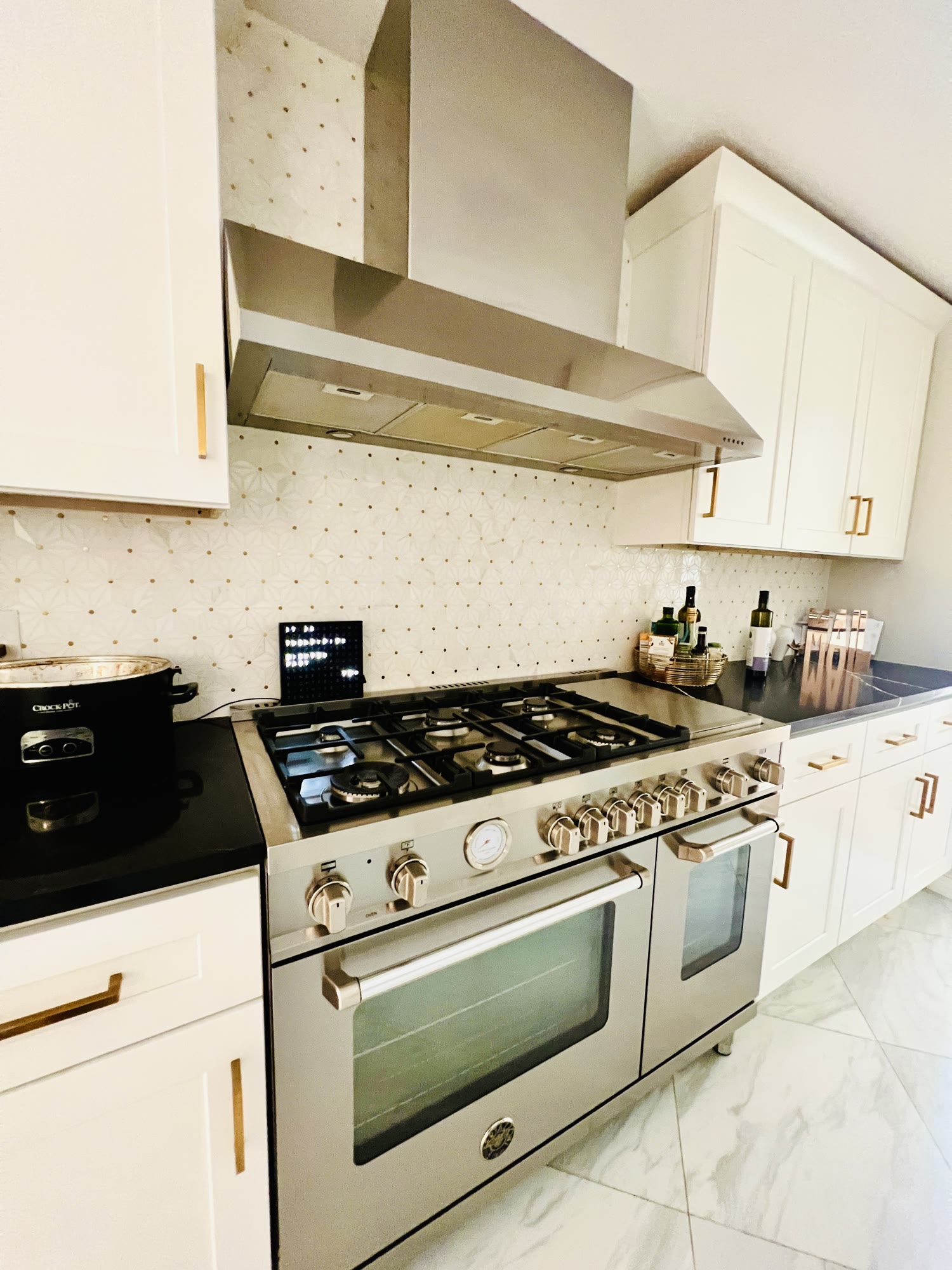 Kitchen range with stainless hood and patterned white backsplash