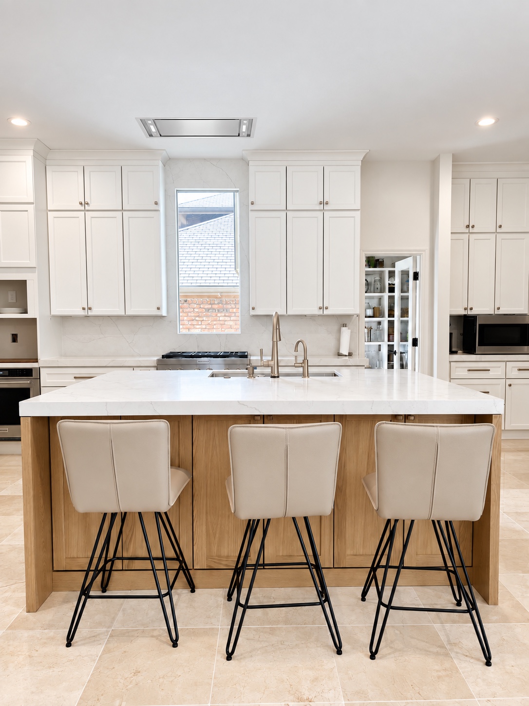 White kitchen with a wood island, three stools, and a flush ceiling hood over the range