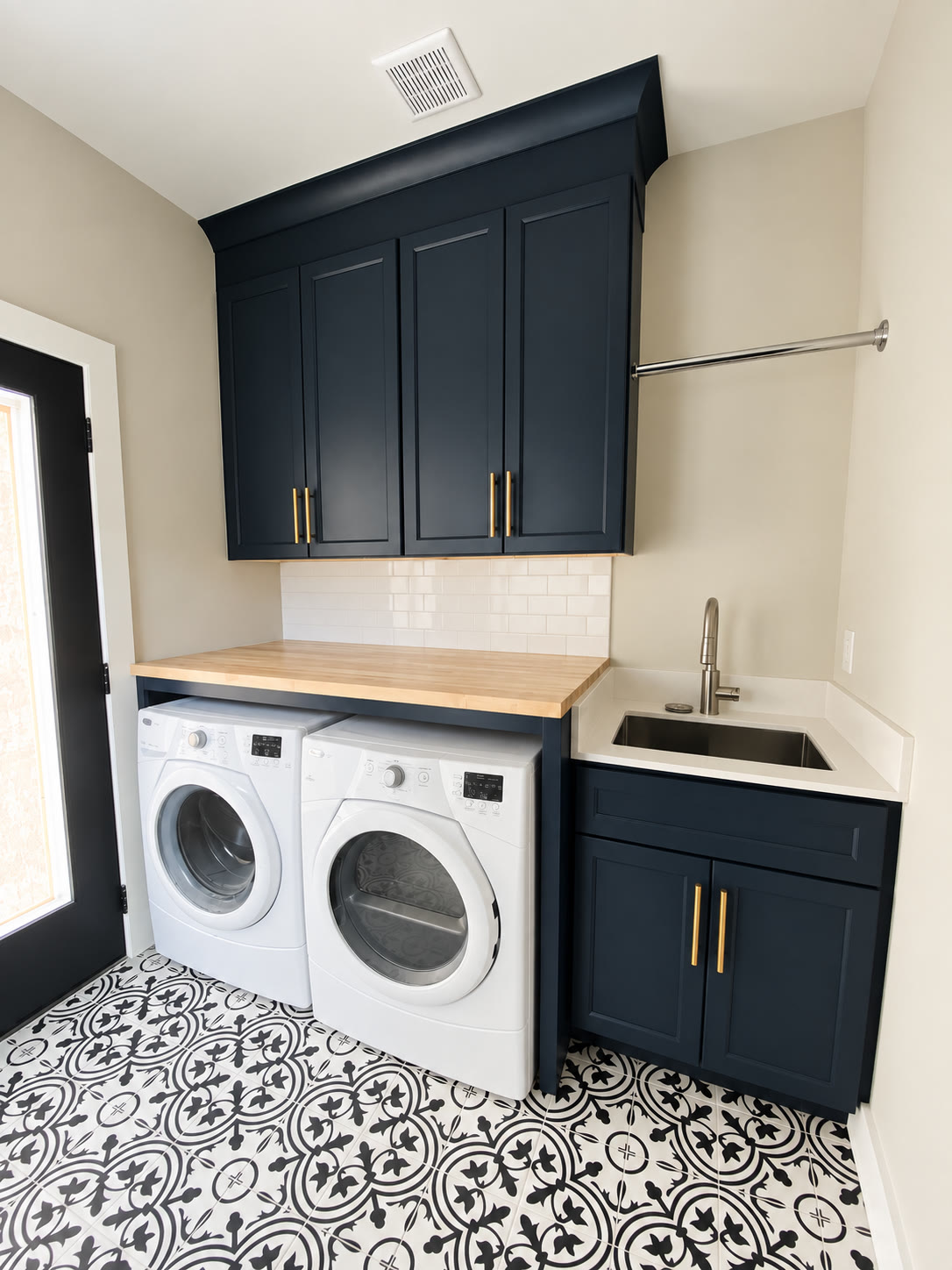 Laundry room with navy cabinets, side-by-side washer and dryer, utility sink and patterned tile