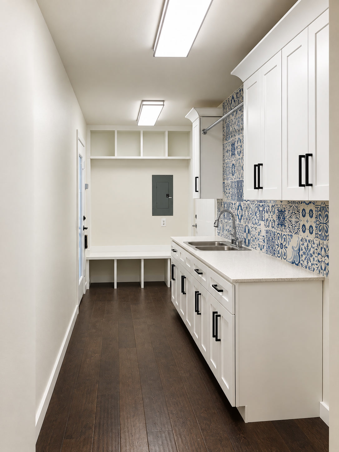 Laundry utility room with white cabinetry, blue patterned tile and a clean dark wood floor