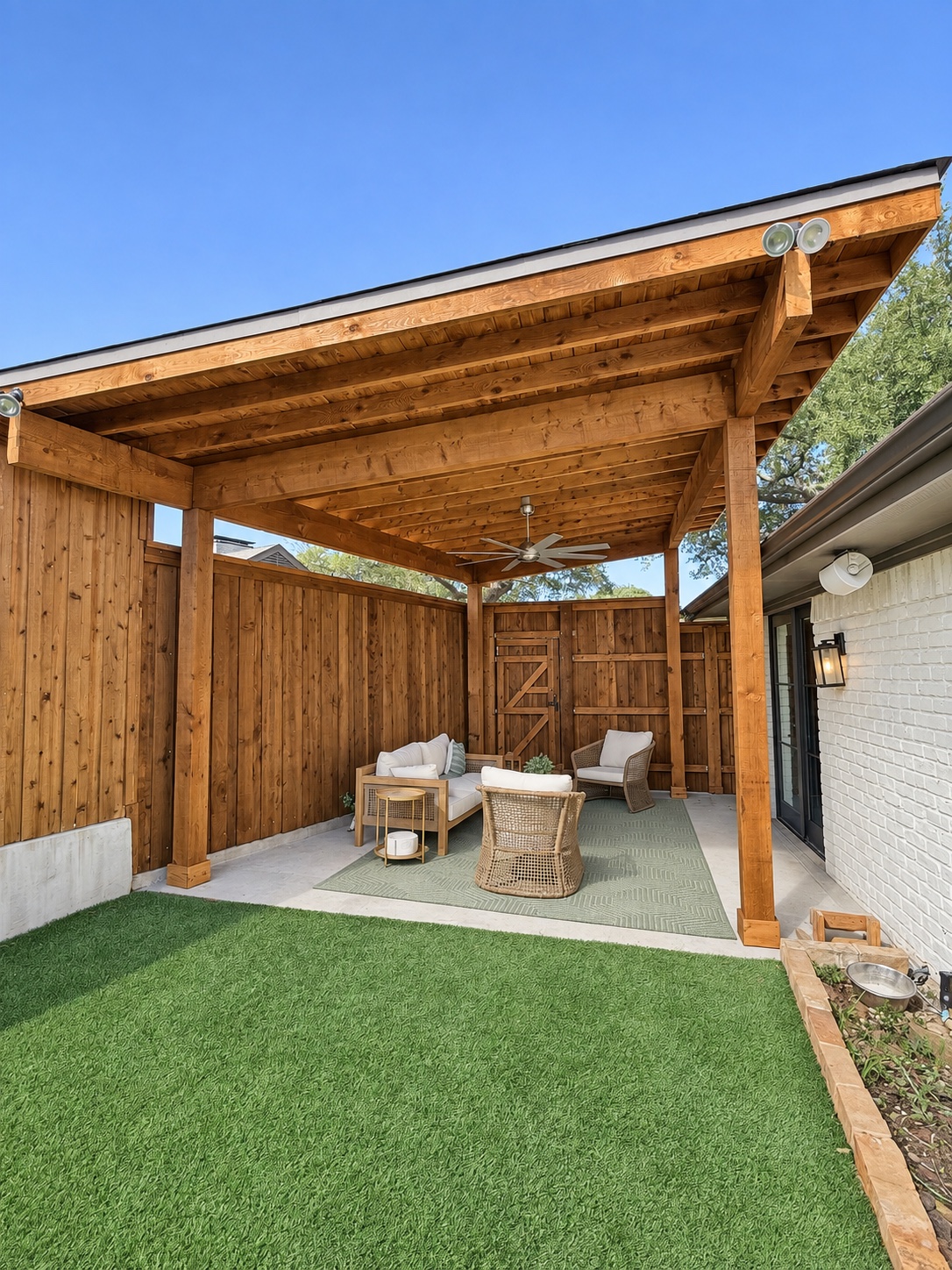 Digitally refined cedar-covered patio with wicker seating, patterned rug and synthetic turf