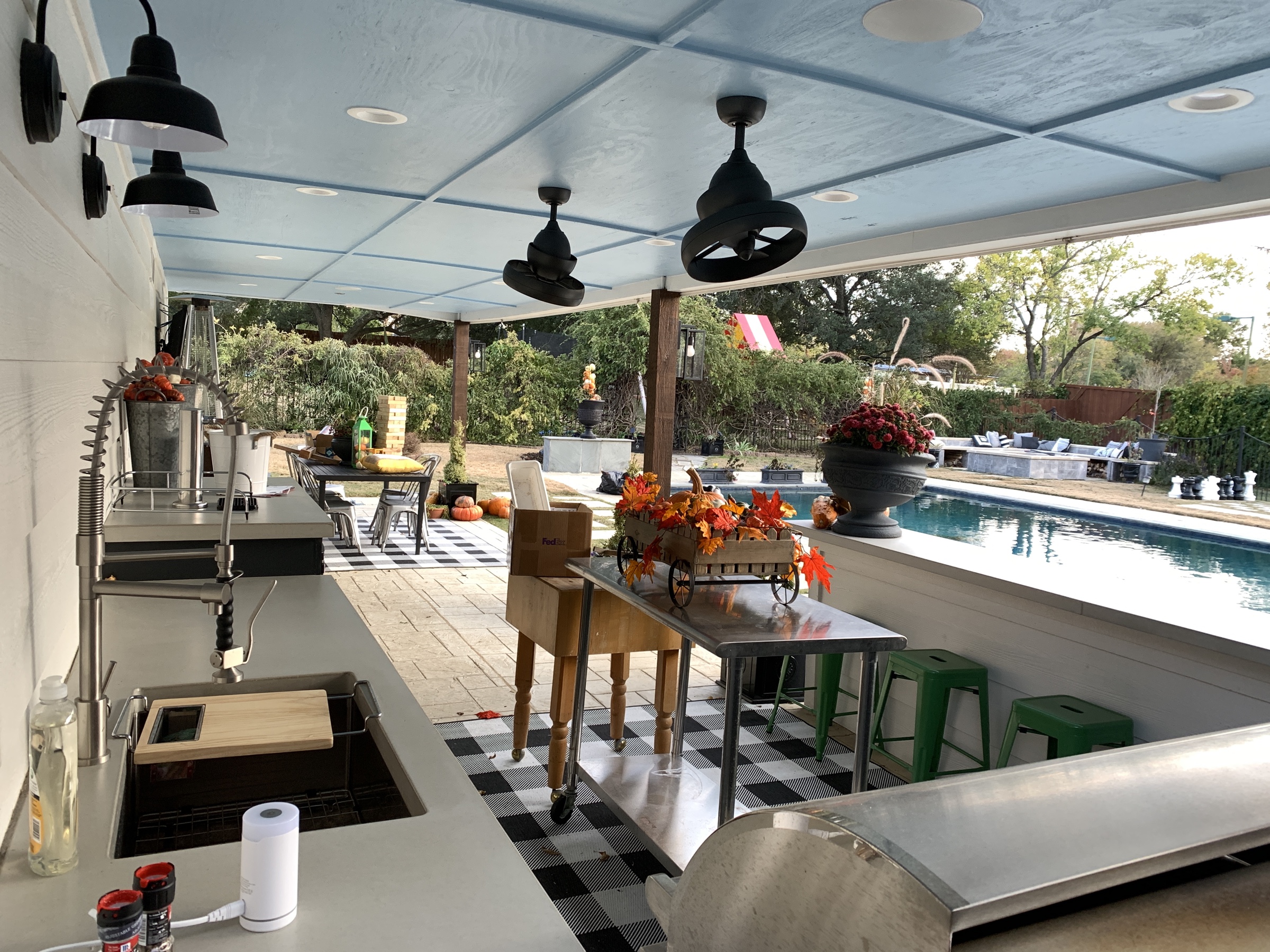 Covered outdoor kitchen with blue ceiling, pool view and open-air dining area