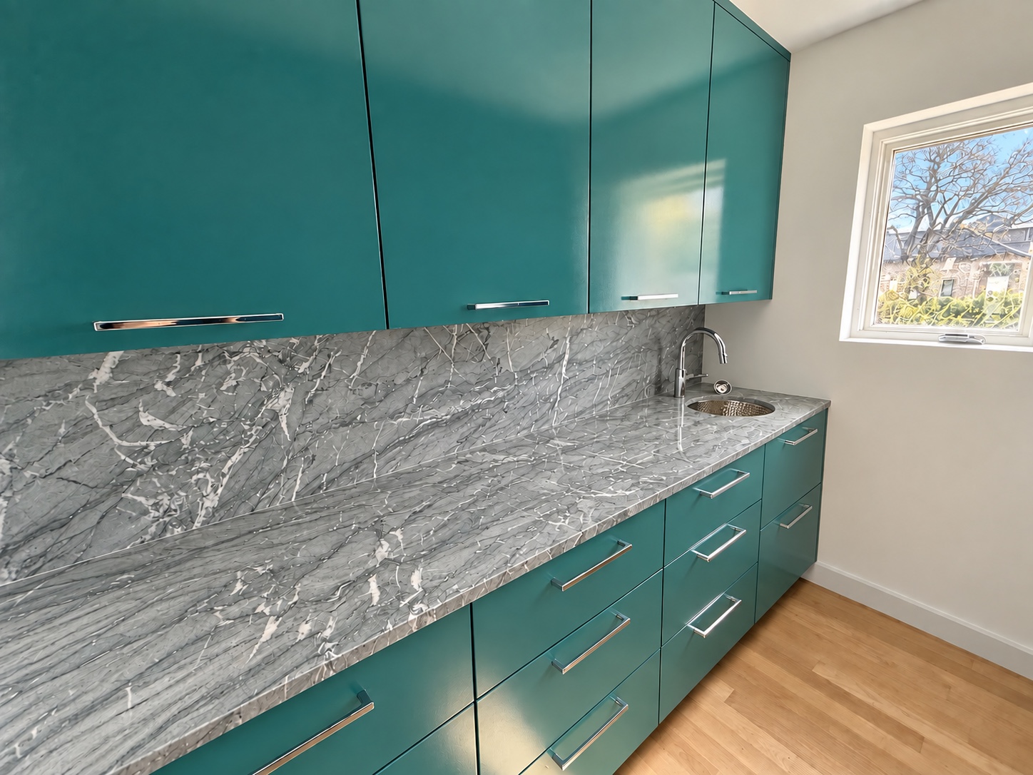 Digitally finished teal pantry with flat-front cabinets, a continuous gray veined stone counter and a prep sink