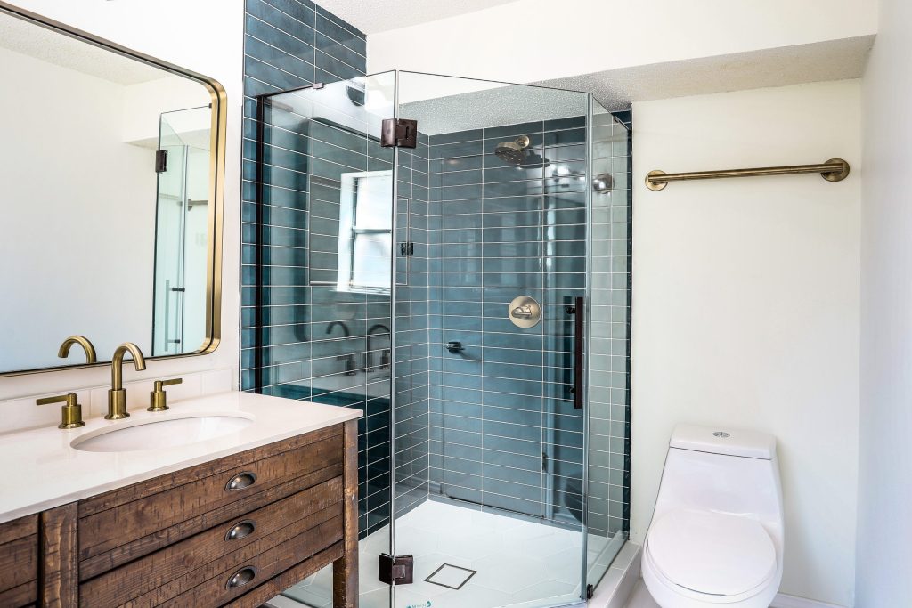 Bathroom with dark blue tile shower and wood vanity