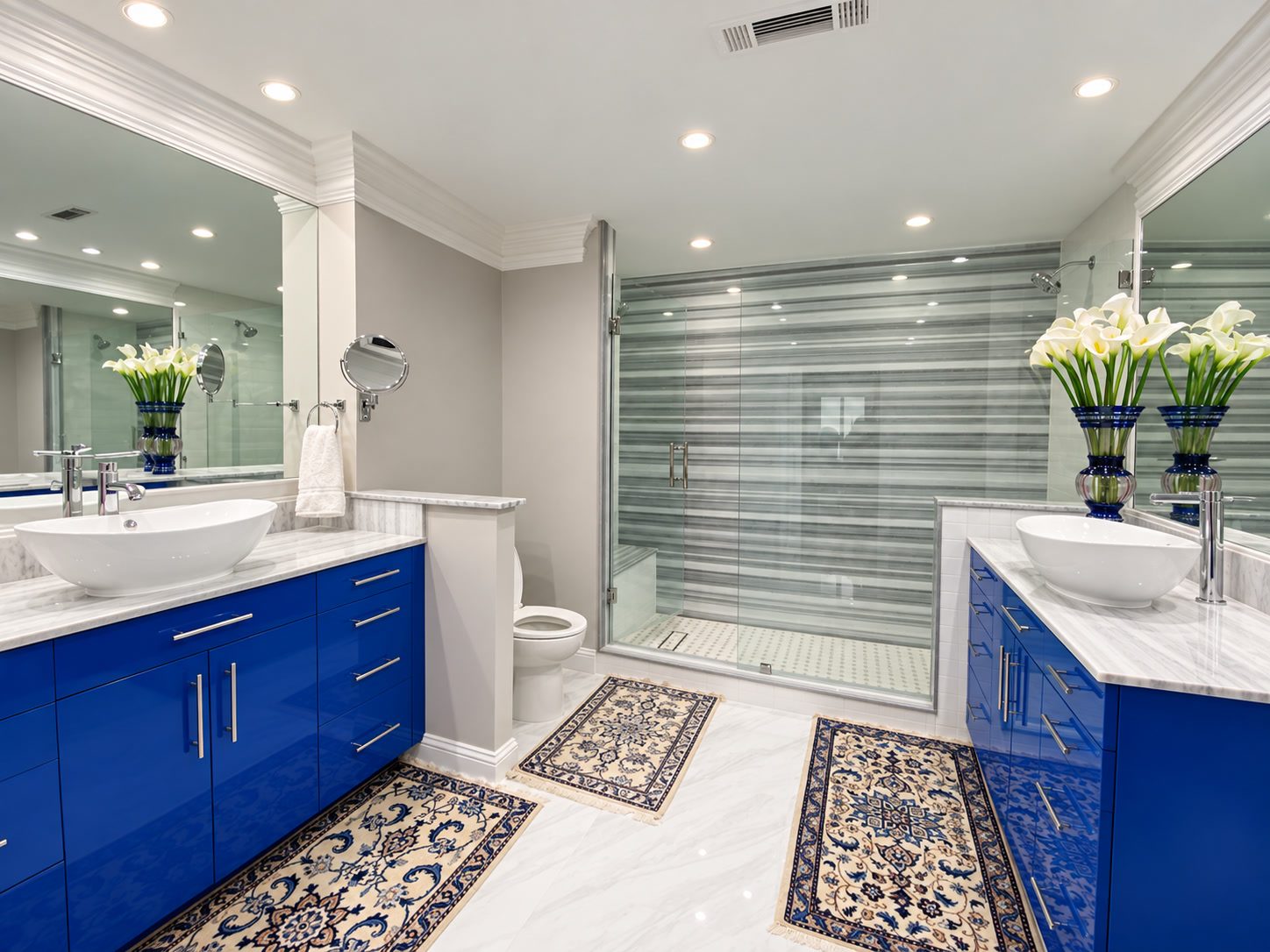 Bathroom with cobalt-blue double vanities, white vessel sinks, striped shower tile and patterned rugs