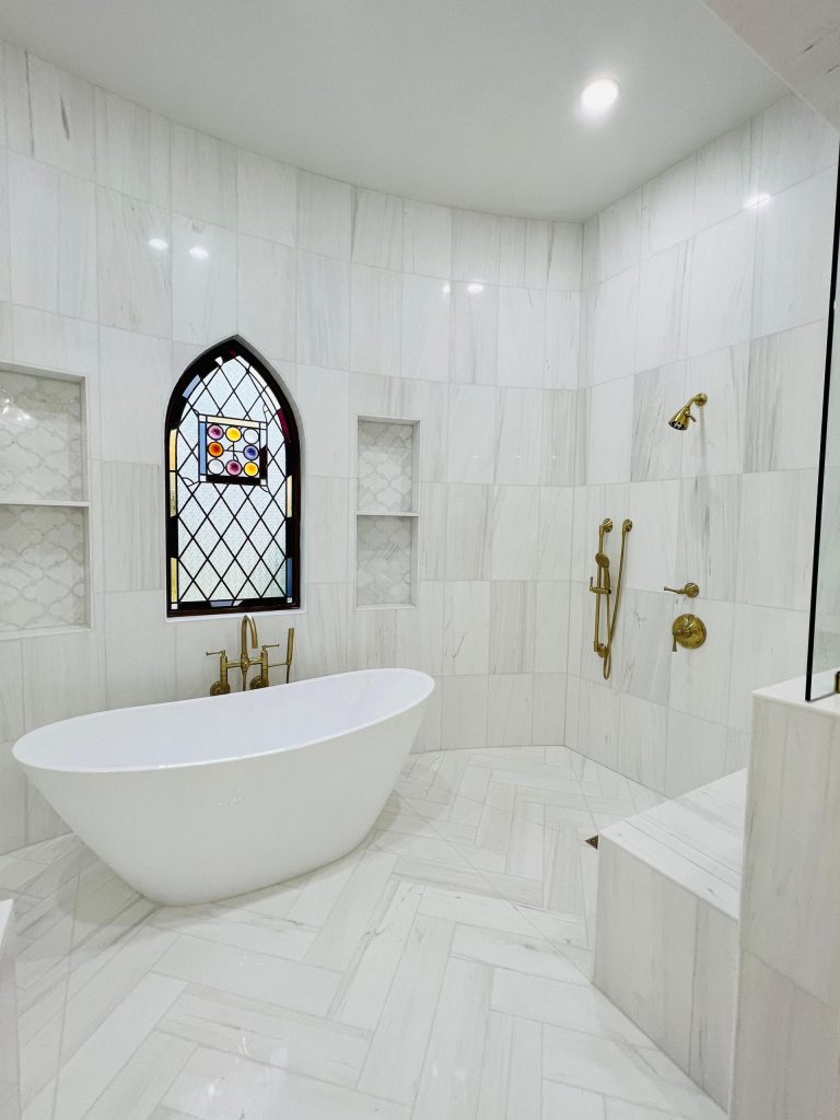 White marble bathroom with freestanding tub and arched window