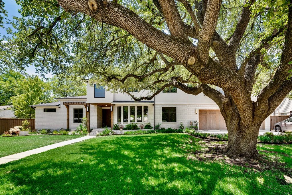 Remodeled house with a large shade tree and deep green lawn