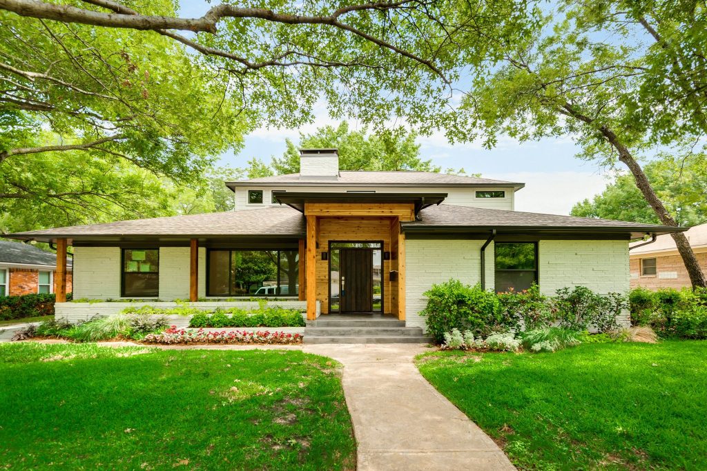 Remodeled home exterior with a broad lawn and mature trees