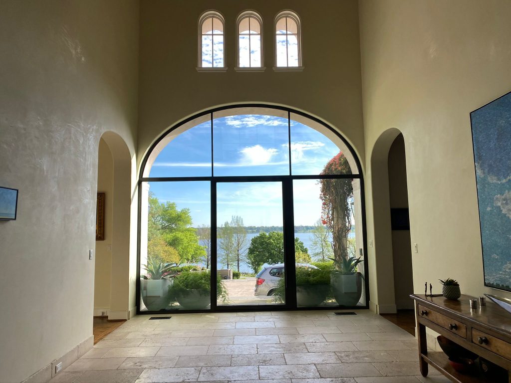 Tall arched window opening an entry hall to outdoor views
