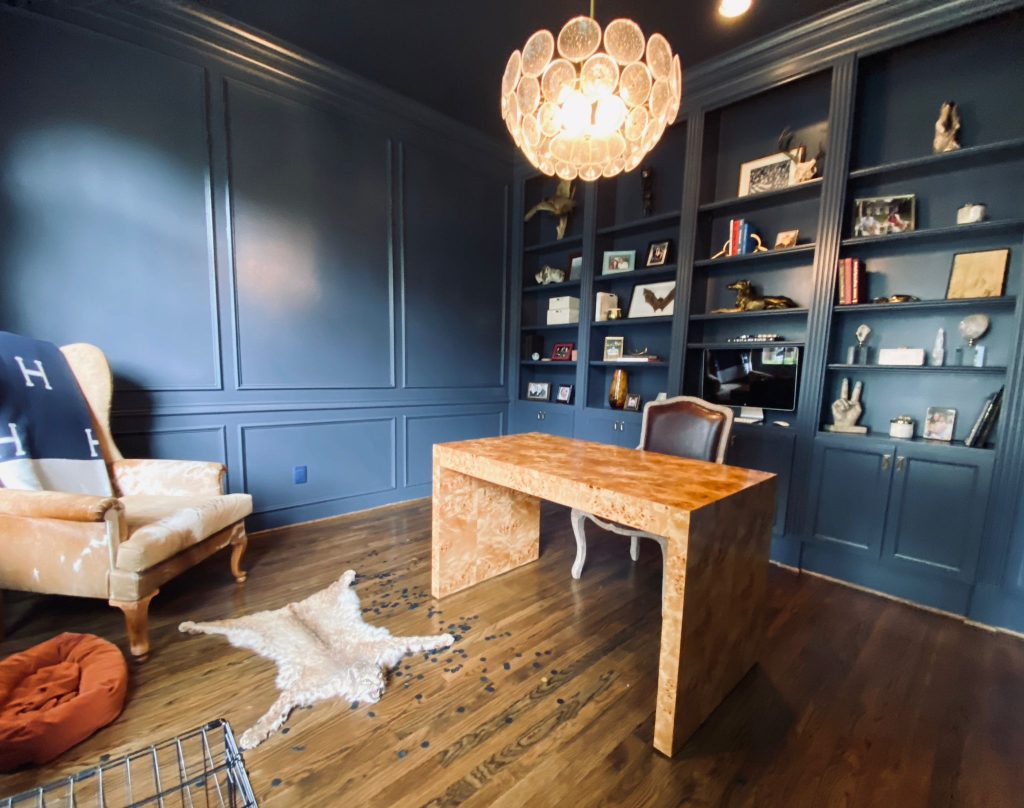 Dark blue home office with built-in shelves and statement chandelier