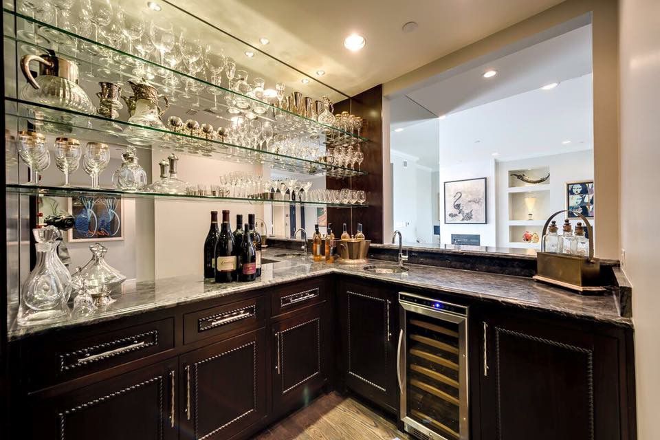 Dark wood home bar with glass shelving and beverage storage
