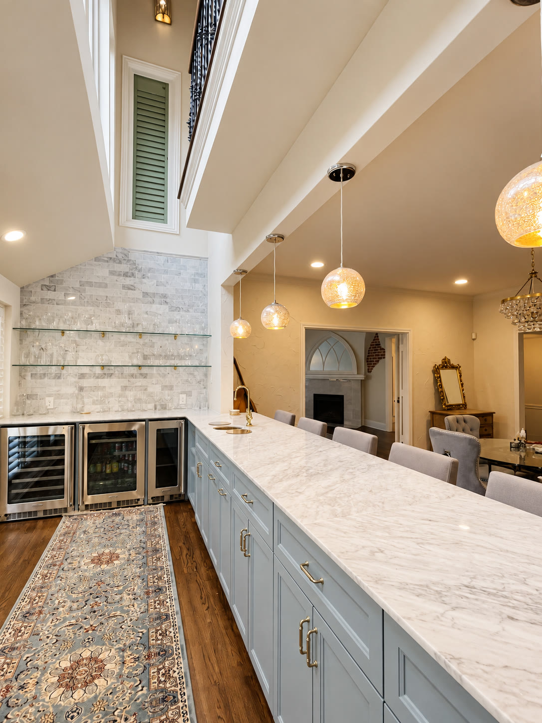 Pale blue home bar with marble counter, beverage refrigerators and glass shelving