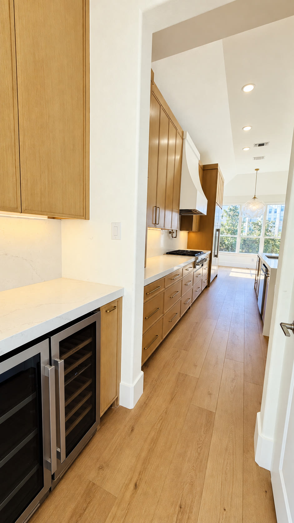 Beverage refrigerators beside a light wood galley kitchen