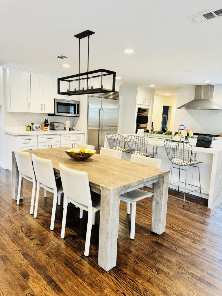 Bright white kitchen and dining area with a large island and dark wood floors